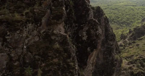 A drone flies around a young athletic female climber hanging on one arm on a Stock Footage 307748214