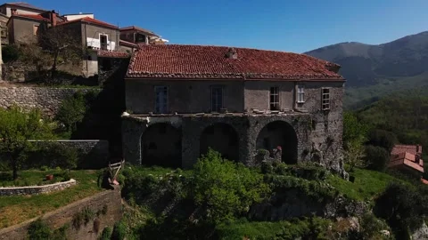 A drone flies away from an old abandoned house in a small mountaintop town  Stock Footage 272752363