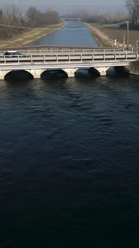 Drone flies away from a river by a bridge Stock Footage 274028274