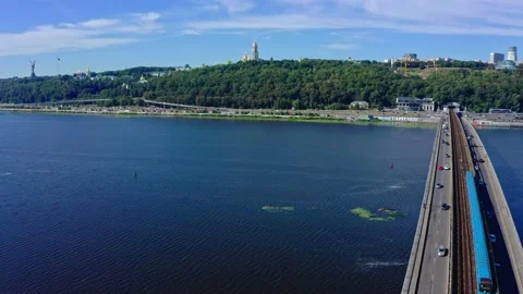 Drone flies back over the Dnipro river and the Metro bridge with moving cars Stock Footage 139747277