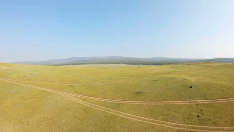 Drone flies back over the yellow meadow and coast Stock Footage 110778622