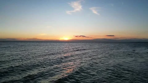 Drone flies back toward the shore at sunset, passing over large rolling waves. Stock Footage 326972948