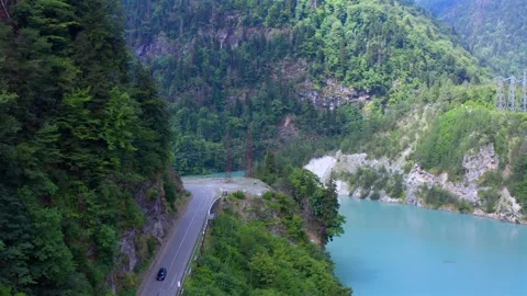 Drone flies backward above Enguri Reservoir road along turquoise water and Vídeo Stock 343543199