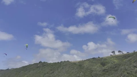 Drone flies backwards below paragliders as camera pans down Stock Footage 326765963