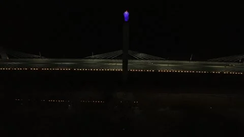 Drone flies backwards from gem atop main pillar at night on bridge Stock Footage 342254512