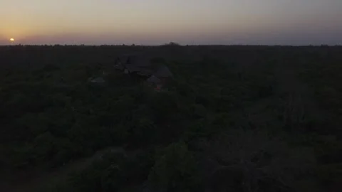 Drone flies backwards from hilltop resort over forest at sunset in Zanzibar Stock Footage 344182359