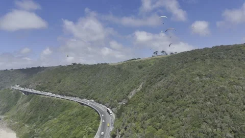 Drone flies backwards over coastal highway as camera pans right Video stock 326769632
