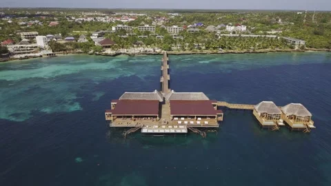 Drone flies backwards over long wooden pier with large cabana Stock-Footage 346470548