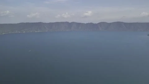 Drone flies backwards from small island in Lake Coatepeque on cloudy day Stock Footage 306364145