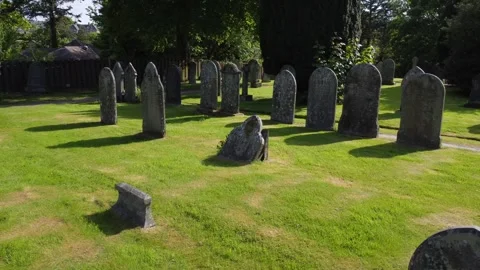 Drone flies backwards through English graveyard, sunny day Stock Footage 242162755