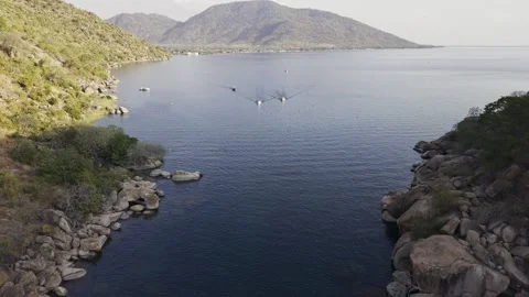 Drone flies backwards through the gap facing Cape Maclear Stock Footage 339549106