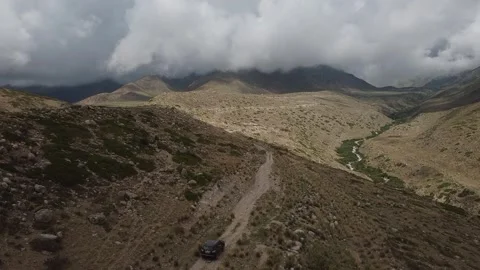 Drone: flies behind a car through a gorge in the mountains of Kyrgyzstan Video stock 266896458