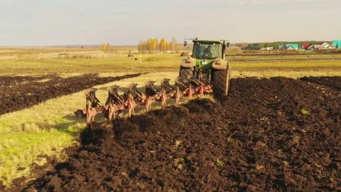 The drone flies behind a tractor plowing a field. Close-up. Stock Footage 148038935