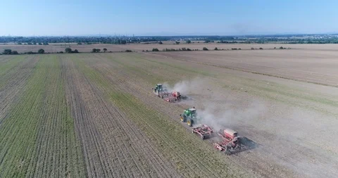 The drone flies behind two tractors that cultivate the field Stock Footage 124901968