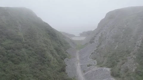 The drone flies between the Mountains in the fog to the Sea Stock Footage