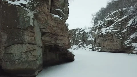 A drone flies between rocks in a snowy canyon in winter Video stock 147627237