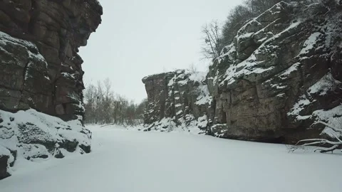 A drone flies between rocks in a snowy canyon in winter Video stock 147627522