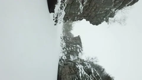 A drone flies between rocks in a snowy canyon in winter. Vertical video. Video stock 147627647