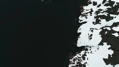 The drone flies in the black waters of the ocean that wash the rocky coast of Stock Footage 169463945