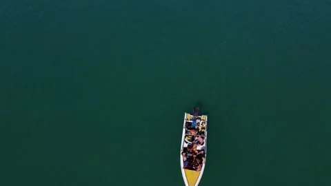 A drone flies close around a floating boat in the lagoon of a picturesque Stock Footage 147528315