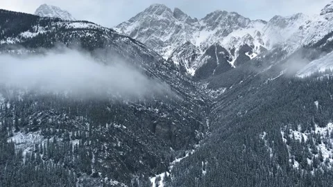 Drone flies up to a cloud descending to the slopes of mountains in Alberta Video stock 143234664