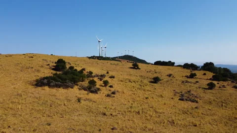 A drone flies down a hill covered in windmills spinning turbines for green Video stock 244829752