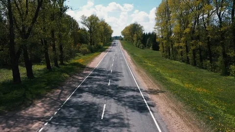 The drone flies exactly over the road to meet a moving car Video stock 107926449