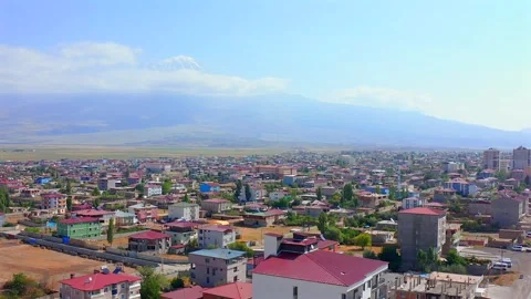 Drone flies forward above Dogubayazit rooftops and a long city boulevard with Vídeo Stock 344835627