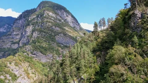 The drone flies forward and up with the camera lifting on a large mountain Video stock 256167706