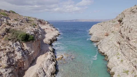 Drone flies forward between narrow rocky Volcanic canyon nature and blue sea. Stock Footage 168254716