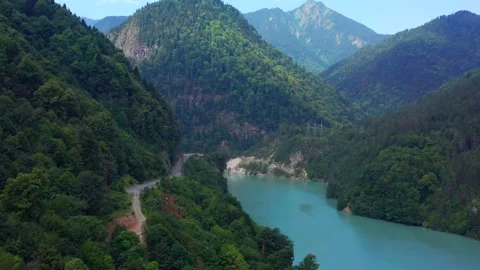 Drone flies forward over Enguri Reservoir through a steep forested gorge in Vídeo Stock 343543166