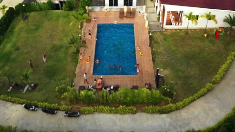 Drone flies forward over residential resort pool with children playing in water 動画素材 308577679