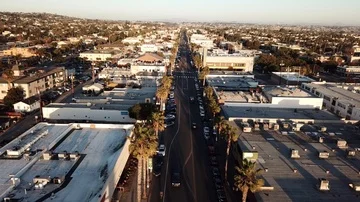 Drone flies forward slowly over California beach town boulevard near sunset Stock Footage 86129659