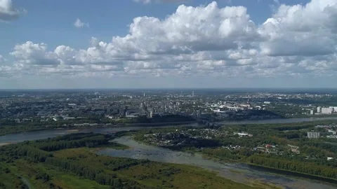 The drone flies high above the outskirts of the green town on the banks of the Stock Footage 169587190