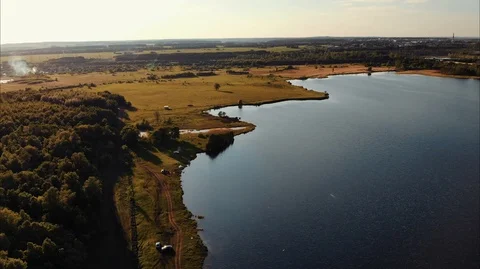 Drone flies high above the shore of the lake, along which there is a dirt road Stock Footage 106926812