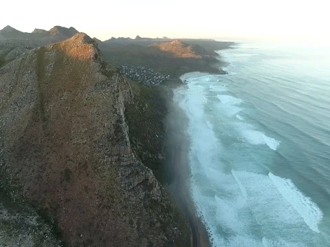 Drone flies high above winding coastal road at sunrise in Cape Town Vídeo Stock 79967268