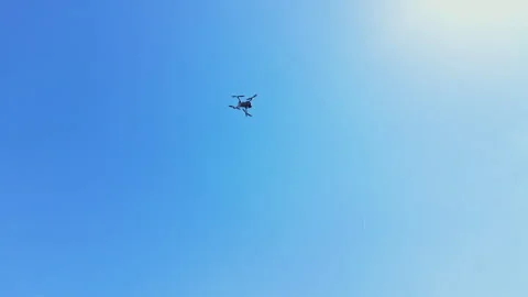 Drone flies high in the clear blue sky during midday near a park in a suburban Stock Footage 344249864