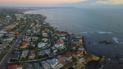 Drone flies high over oceanfront mansions with La Jolla background at sunset Stock Footage 97184911