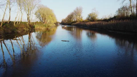 Drone flies just above river surface towards men sitting in two boats in autumn Stock Footage 263207956