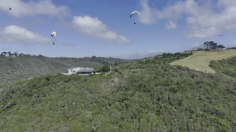 Drone flies left as paragliders fill the sky on a sunny day on the Garden Route Stock Footage 326702372