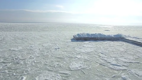 Drone flies low and backwards over a small pier in the frozen Black Sea Stock Footage 72586916