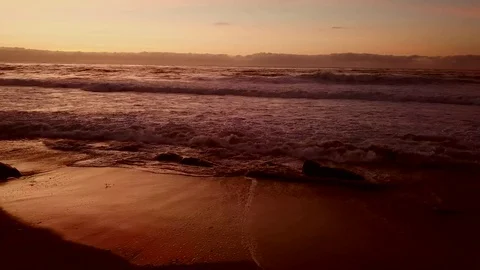 Drone flies low and slow along rock beach after sunset 库存影片 84775137