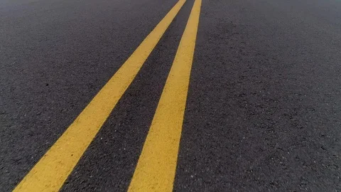 Drone Flies Low Over Double Yellow Curvy Line On Asphalt Stock Footage