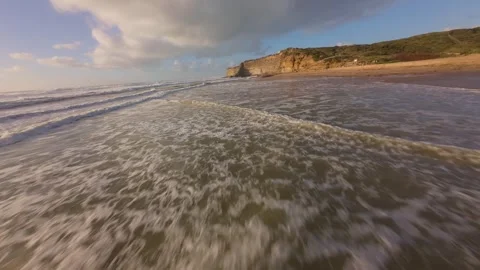 Drone flies low over foamy surf hitting rocky shore Stock Footage 344551337