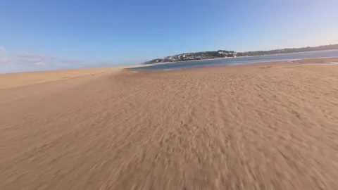 Drone flies low over sunlit beach meeting turquoise sea Stock Footage 344582114