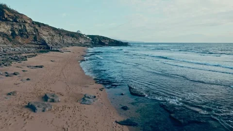 Drone flies low over the surface of the water along the rocky shore during .. Stock Footage 254622661