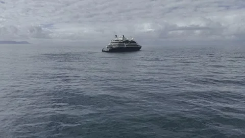 Drone flies out to sea low over water toward cruise ship departing the area Vídeo Stock 327479559