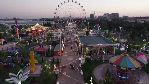 A drone flies over an amusement park with carousels and a Ferris wheel Stock Footage 253632802