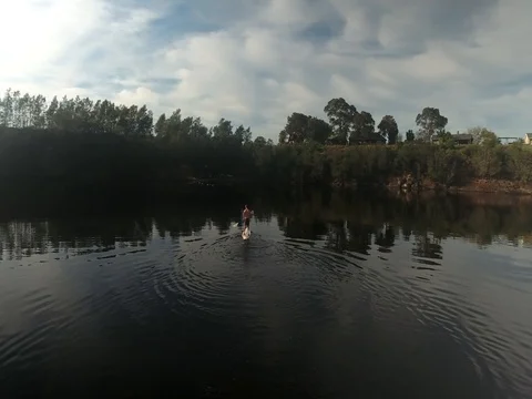 Drone flies over and around stand-up paddleboarder in dam Vídeo Stock 79961085