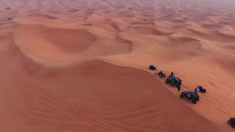A drone flies over ATVs standing on the sand dunes of the desert against the Stock Footage 244770918